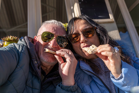 happy middle aged couple in love taking a selfie while eating a snack in an outdoor pubの写真素材