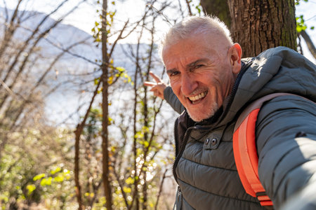 happy middle aged man taking a selfie surrounded by natureの写真素材