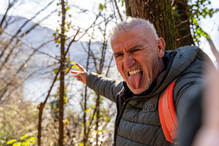 happy middle aged man taking a selfie surrounded by natureの写真素材