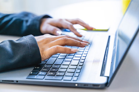 close up of female hands of a businesswoman typing on a laptop keyboard in an officeの写真素材