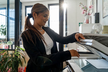 elegant business woman activating laser printer to scan a document in a modern officeの写真素材
