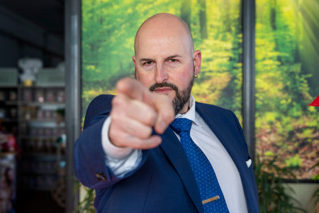 man in elegant suit pointing finger at the camera in his officeの写真素材