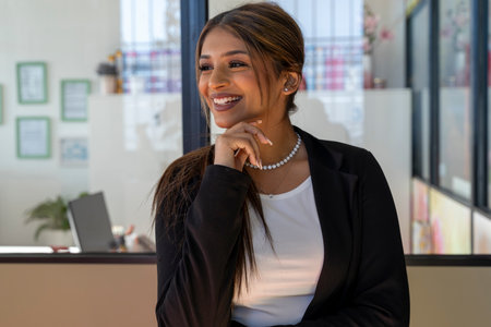 portrait of young elegant business woman smiling in front of glass window in officeの写真素材