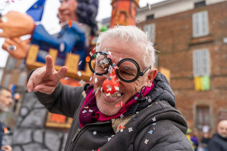 handsome middle aged man taking a selfie wearing a funny mask posing during a carnival parade in the streetの写真素材