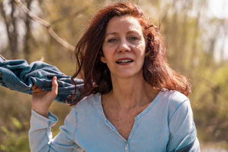 portrait of smiling and charming woman with red hair walking in spring natureの写真素材