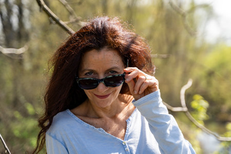 portrait of smiling and charming woman with red hair walking in spring natureの写真素材