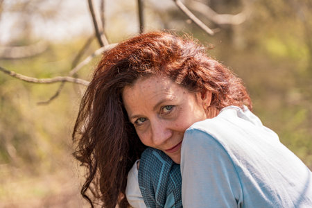 portrait of smiling and charming woman with red hair walking in spring natureの写真素材