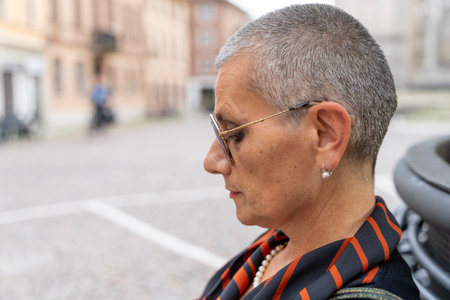 profile portrait of middle aged woman with shaved gray hair sitting outdoorsの写真素材