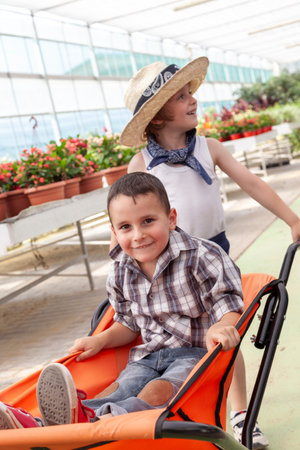 Children playing in greenhouse with wagon, friendship concept