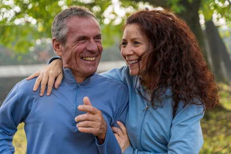 Active senior couple laughing and smiling, embracing outdoors in a park