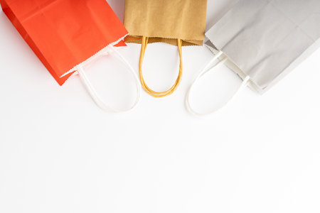 Three paper bags lying on a white background, handles turned to the center.の写真素材