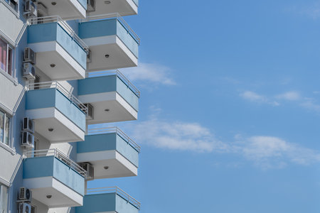 A row of identical small balconies of a high-rise building against a blue sky.の写真素材