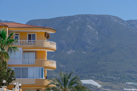 Part of a beautiful yellow house against the backdrop of a mountain and a blue sky.の写真素材