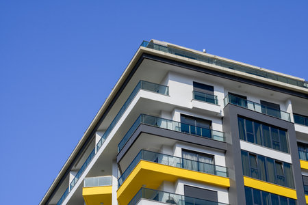 A small fragment of a modern apartment building against a blue sky.の写真素材