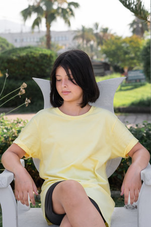 A young girl sits alone on a wooden throne in a city park.の写真素材