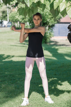 Teenage girl doing muscle stretching exercise in a city park. vertical shot.の写真素材