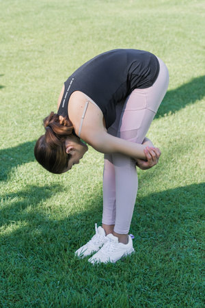 The girl stretches the muscles of the back against the background of greenery. outdoor exercises.の写真素材