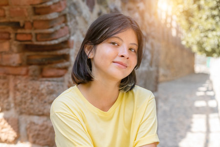 Portrait of a young girl on the background of a stone wall with an arch. A girl with dark hair poses for the camera.の写真素材