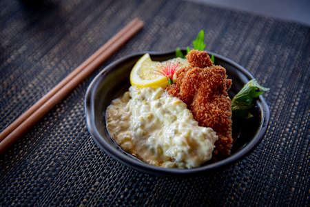 Nanban Chicken Katsu fried chicken appetizer in the traditional Japanese ramen restaurant, with a black plate on a black mat in a black scene backgroundの写真素材