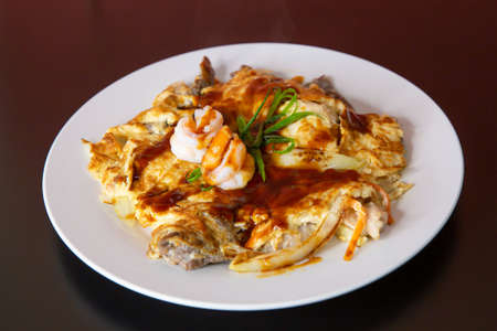 Prawn shrimp chicken pan fried omelette of traditional Cantonese yum-cha Asian gourmet cuisine meal food dish on the white serving plate and brown red tableの写真素材