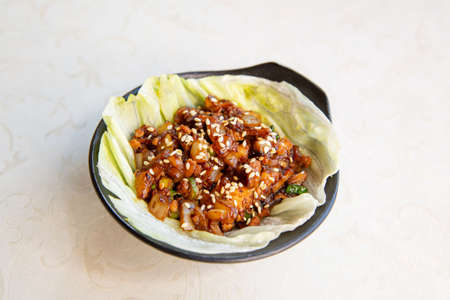 Stir-fried pork stew with lettuce of traditional Cantonese yum-cha Asian gourmet cuisine meal food dish on the white serving plate and white tableの写真素材