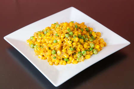 Salted egg sweet corn of traditional Cantonese yum-cha Asian gourmet cuisine meal food dish on the white serving plate and brown red tableの写真素材