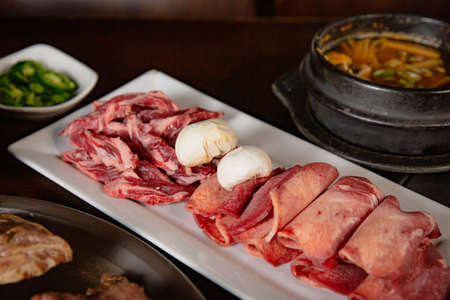 Korean Grilled BBQ combo with wagyu beef set on the traditional grill table, with lettuce, soup, mushroom and pickle dishesの写真素材