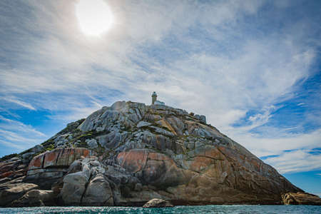 South Point Lighthouse on Stone rock mountain forest seascape in Cruising tour view in the Bass Strait at Wilson Promontory Victoria Australia, blue sky and blue seaの写真素材