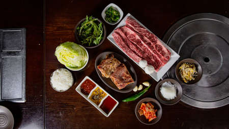 Top view of Korean Grilled BBQ combo with wagyu and marinated beef set on the traditional grill table, with lettuce, dipping sauce and pickle dishesの写真素材