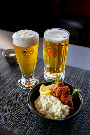 Nanban Chicken Katsu fried chicken with beer appetizer in the traditional Japanese ramen restaurant, with a black plate on a black mat in a black scene backgroundのeditorial素材