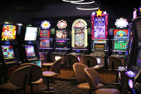 Pokie machines in local hotel casino with neon light and empty seats during pandemicのeditorial素材