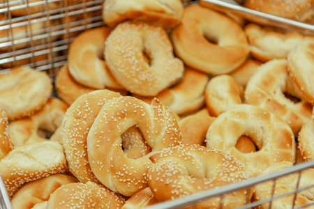Homemade traditional bagels with sesame ready for use, in a tray with a tong, in bakery shopの写真素材