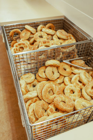 Homemade traditional bagels with sesame ready for use, in a tray with a tong, in bakery shop