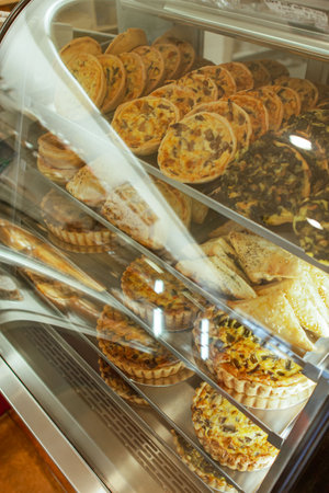 Traditional European bakery shop interior, quiche, cake pastry, meet pie, puff in window displayの写真素材