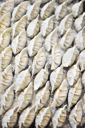 A pile of raw Homemade Momo asian dumplings with flour covered, ready to cook, selective focusの写真素材