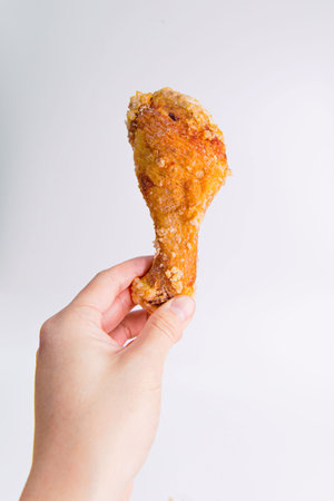 Customer Holding an Asian Classic Fried Chicken Leg, Marinated with Taiwanese Seasoning on an Isolated White Backgroundの写真素材