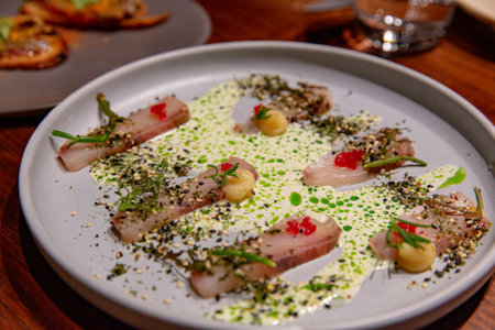 Artistic Presentation of Sliced Raw Fish, Accented with Dots of Sauce and Herb Sprinkles