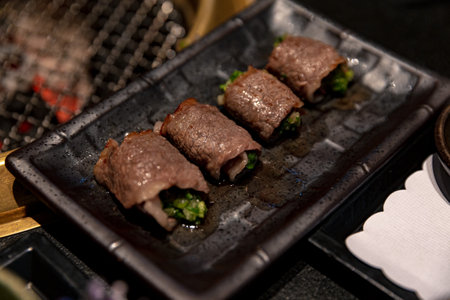 Exquisite Beef Negimaki with scallions, elegantly presented on a sleek black plate, showcasing the traditional Japanese dish in a refined settingの写真素材