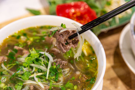 Vietnamese Pho with Chopsticks Holding Beef Over Aromatic Broth, Perfect Blend of Flavors and Texturesの写真素材
