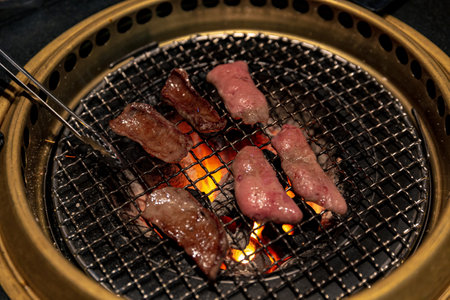 Ox Tongue Marinated and Ready for Grilling on a Gold Grill Over Charcoal Fire for Traditional Korean BBQ, Offering Rich Flavors and Smoky Tasteの写真素材