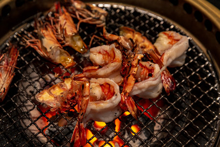 Close-up of beautifully charred prawns over glowing embers in a traditional yakiniku setting, emphasizing the seafood's rich texturesの写真素材