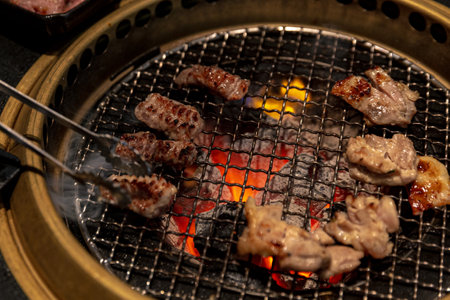 Close-up of succulent sirloin steaks and chicken with perfect grill marks, served on a yakiniku grill amidst an ambient restaurant settingの写真素材