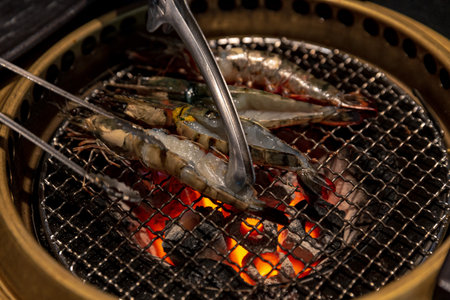 Fresh prawns being expertly grilled over a fiery charcoal, showcasing the art of Japanese yakiniku...