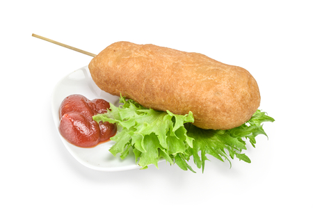 corn dog on plate with ketchup and lettuce over white background.の写真素材