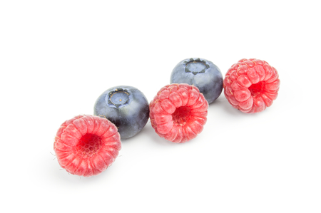 Raspberries and blueberries in row isolated on white.の写真素材