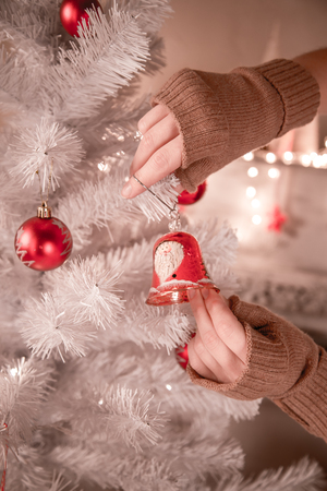 Girl hanging decorative toy bell on Christmas tree branch.の写真素材