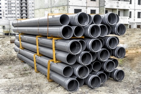 Stacks of grey plastic pipe in a construction site.