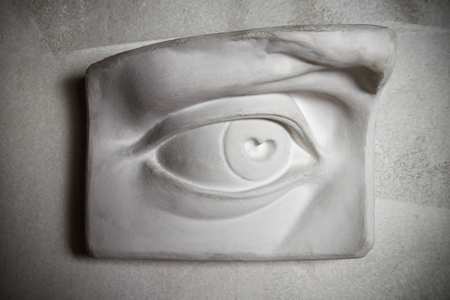 Sculpture of eye on the grey wall.の写真素材