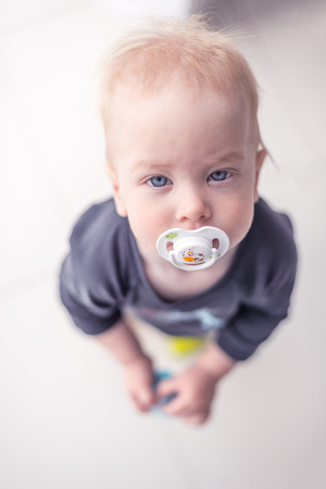 Sweet baby girl with a soother standing