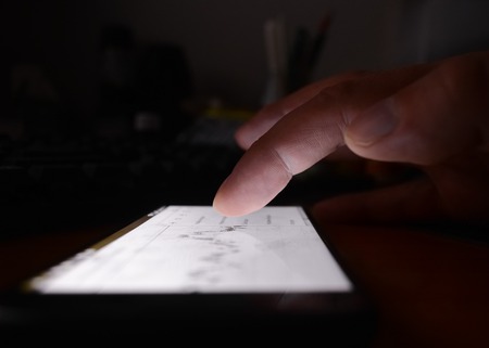 close-up finger touching on communicator electronic device on nightの写真素材